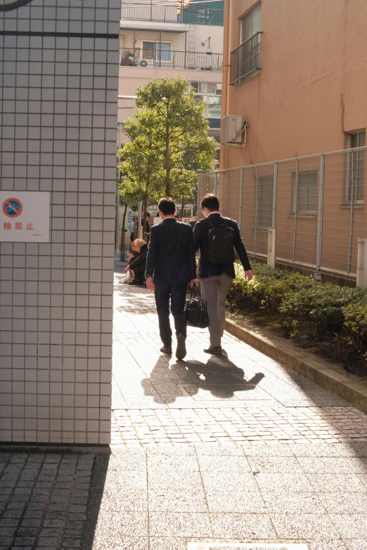 two men walking down a city street with a traffic light