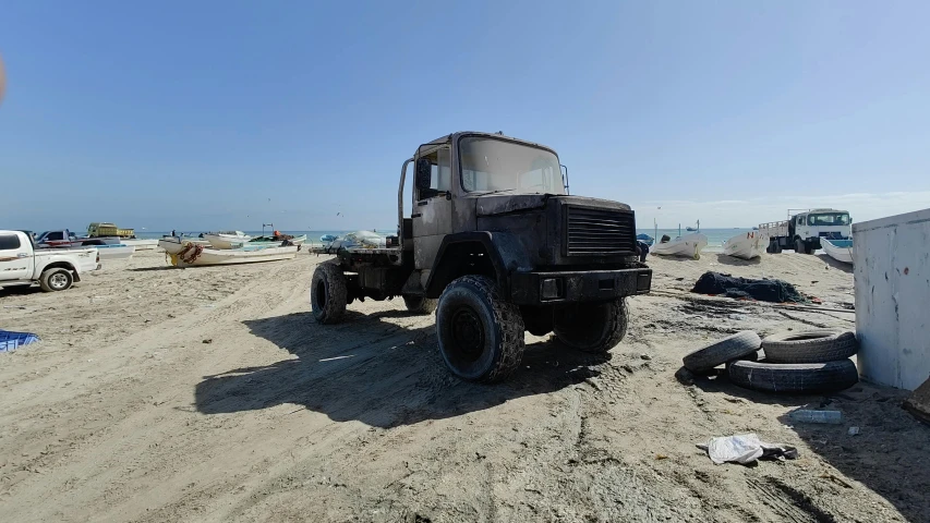 the truck is parked in the sand and has black rims