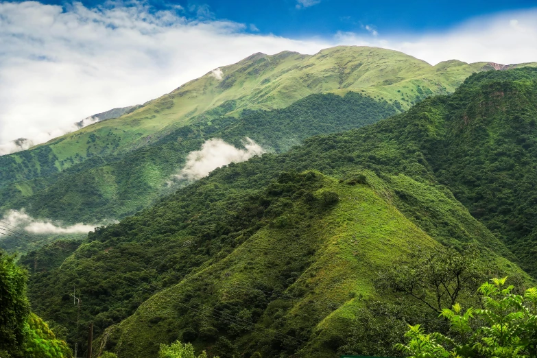 green hills with small patches and scattered clouds in a valley