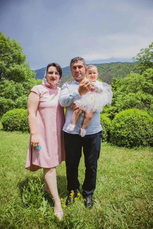 two people standing next to a small child in a field