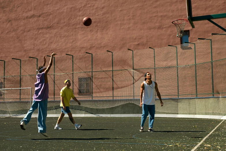 three people playing with a ball while a man jumps up to catch the ball