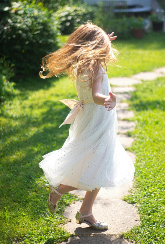 a little girl wearing a princess costume running down a path