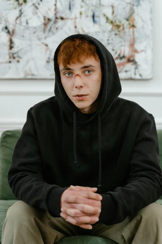 young red haired man with hands folded sitting on a couch