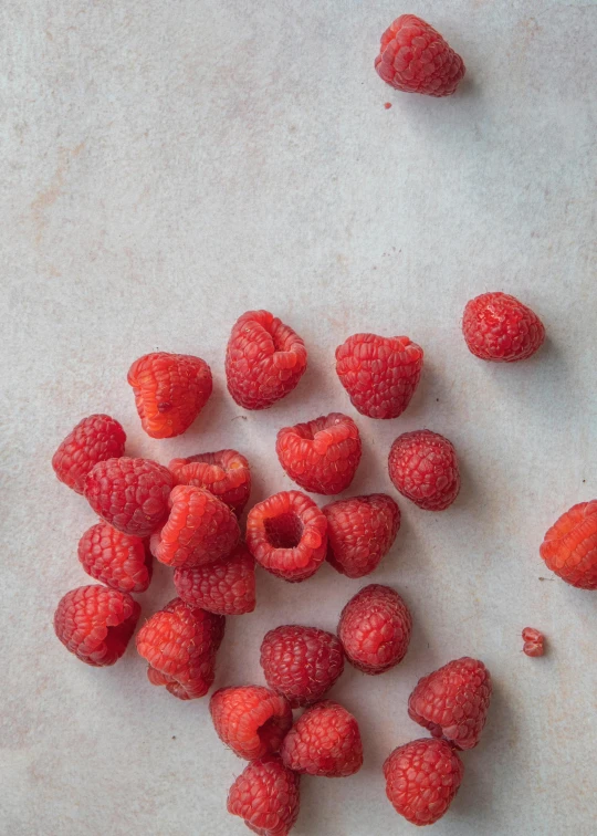 raspberries on a white surface next to a peeled one