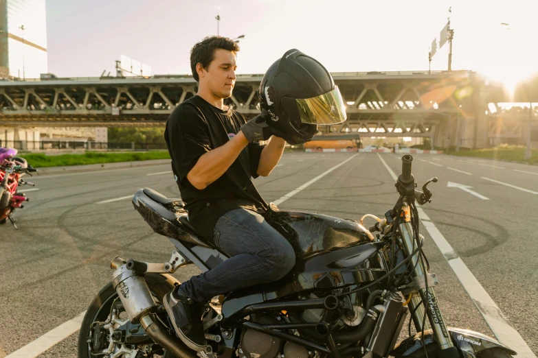 a man holding up his motorcycle helmet while standing next to the bike