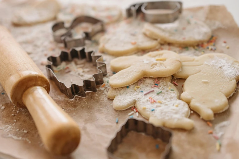 several sugar cookies with icing being made and some dough roller