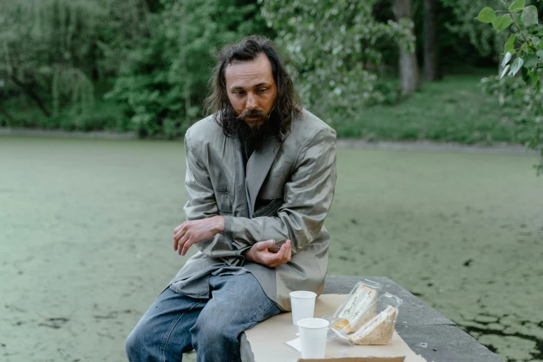 man sitting on wooden table in front of body of water