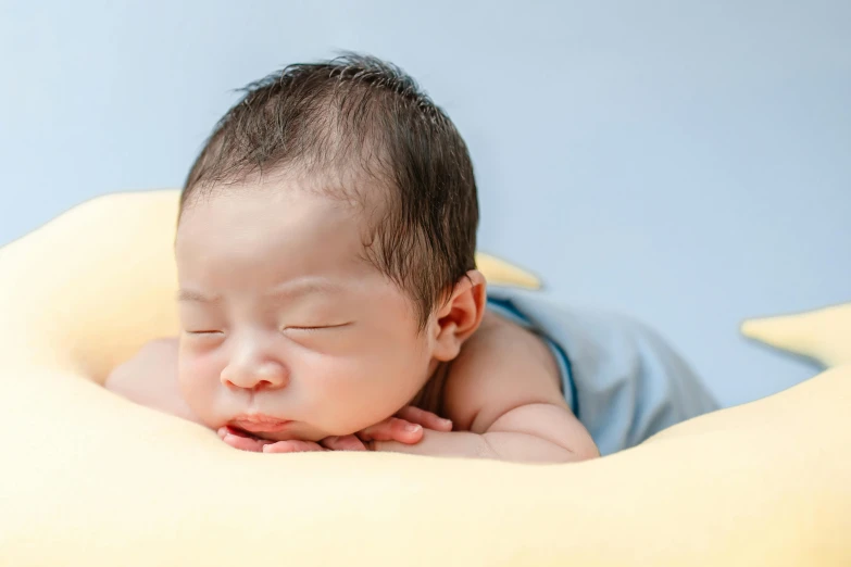 a baby laying on a pillow with a blue blanket