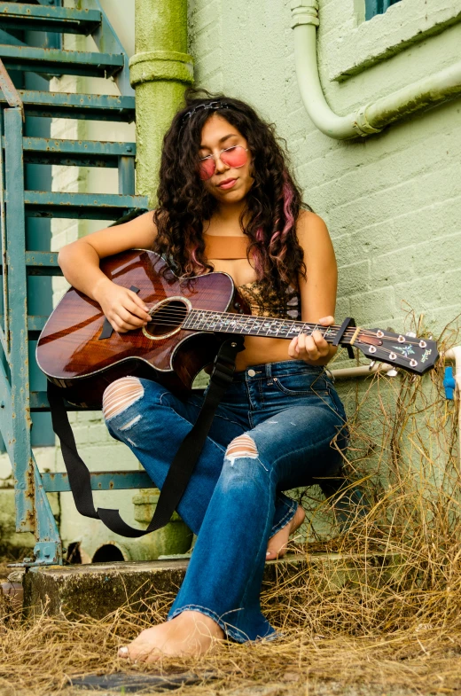 a woman wearing glasses sitting with a guitar in her lap