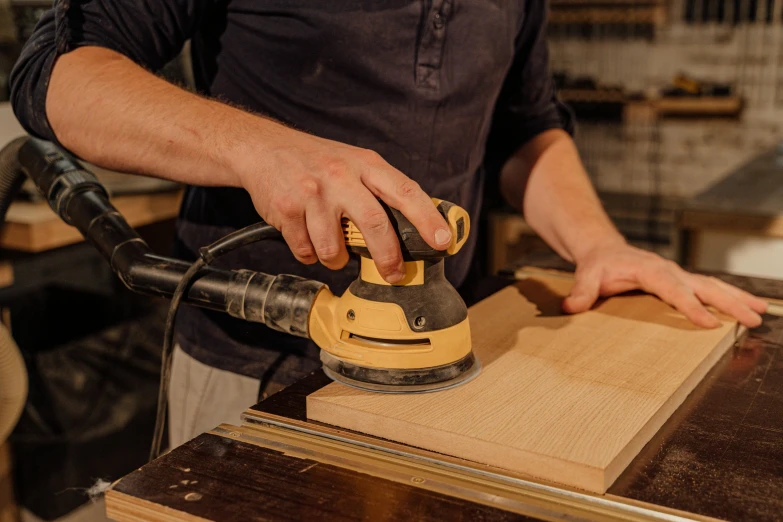 person  planks with a corded orbital sander