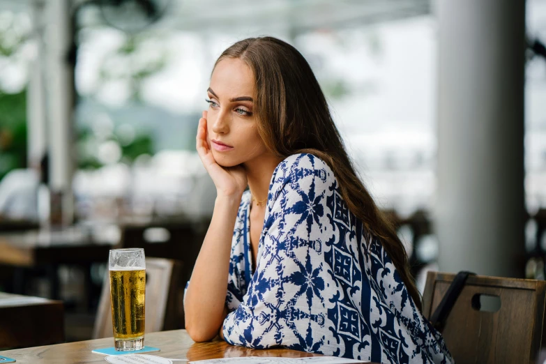 a woman sitting at a table with a drink and book on it