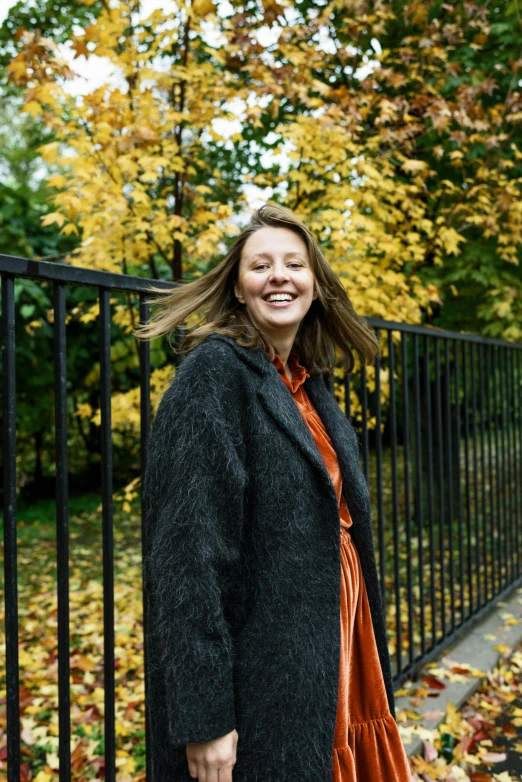 woman in orange dress smiling behind the railing