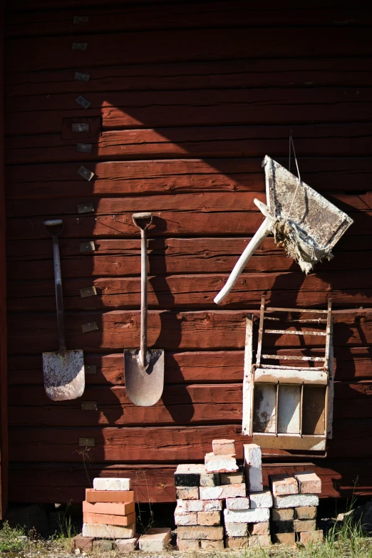 an old wood shed with an empty ladder and garden tools