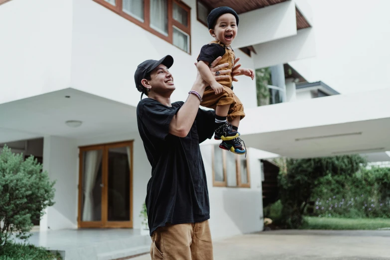 two people holding a child in front of a building