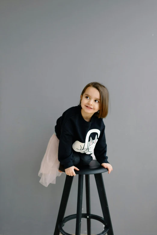 a child poses on top of a stool