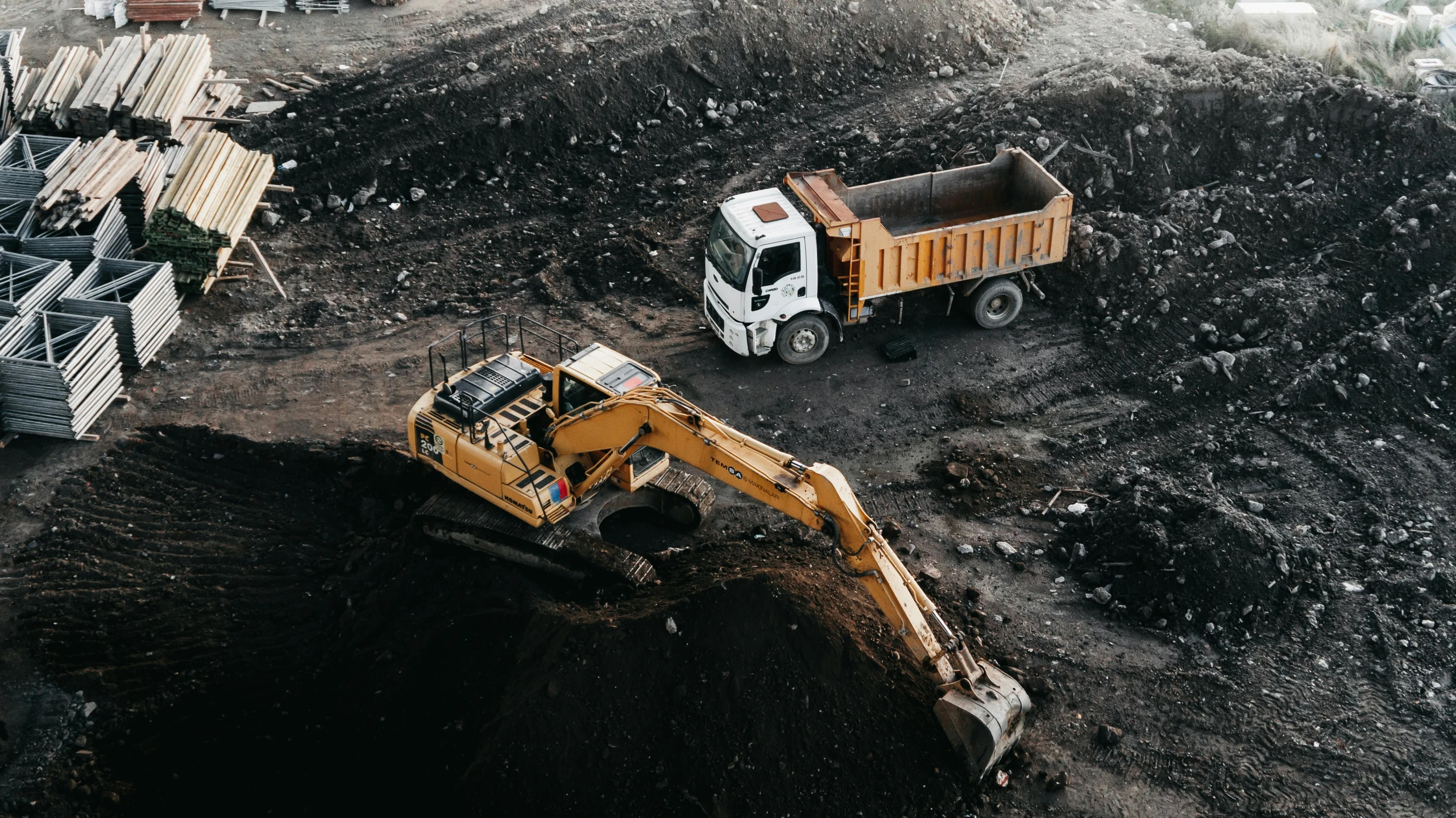 a dump truck is dumping dirt behind a truck