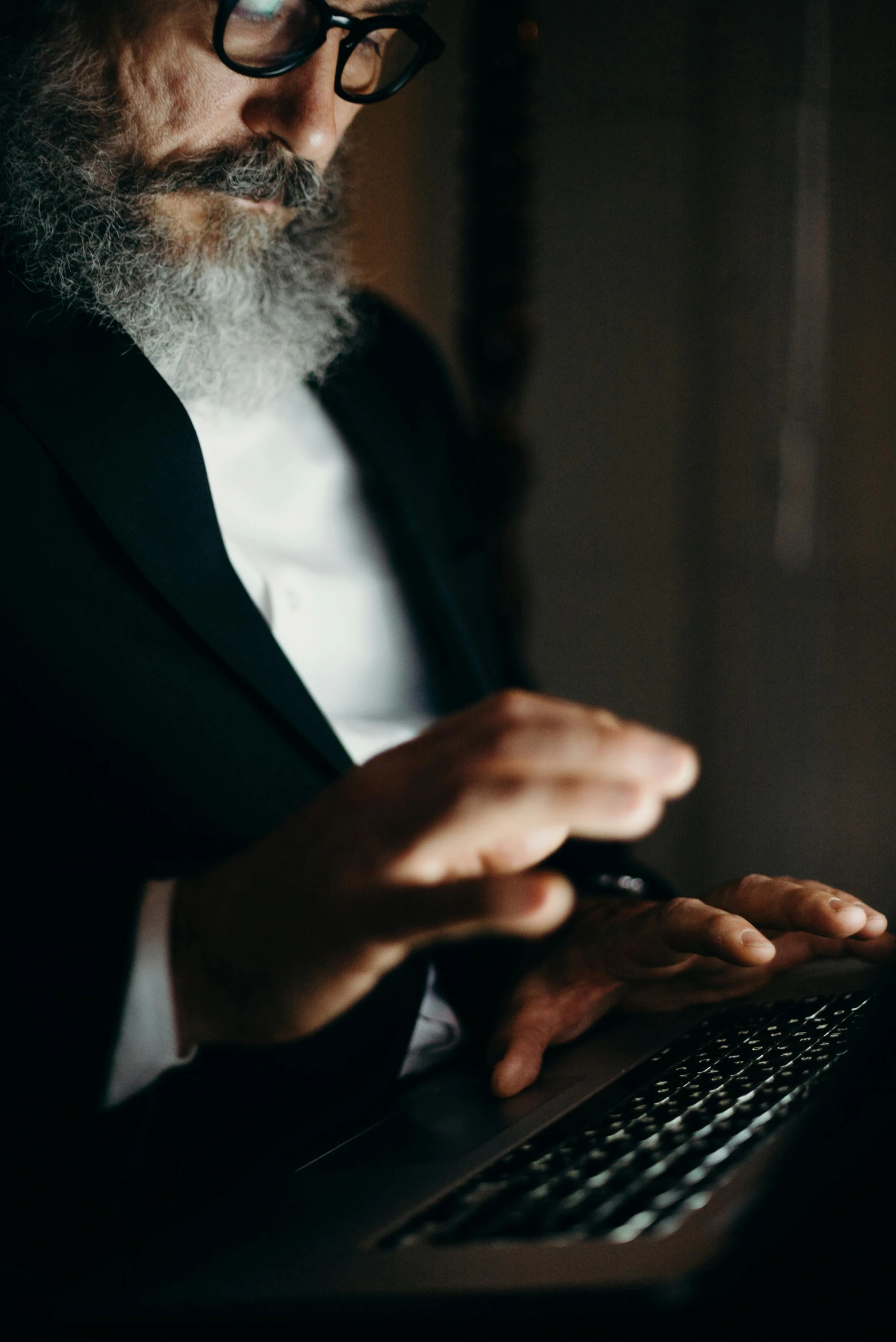 a man in tuxedo uses a laptop computer