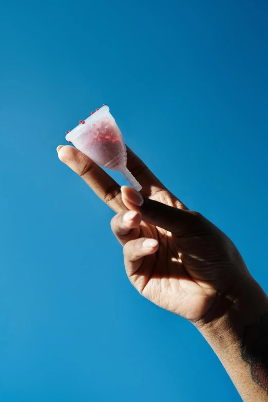 the hand holds an item of powder against the blue sky