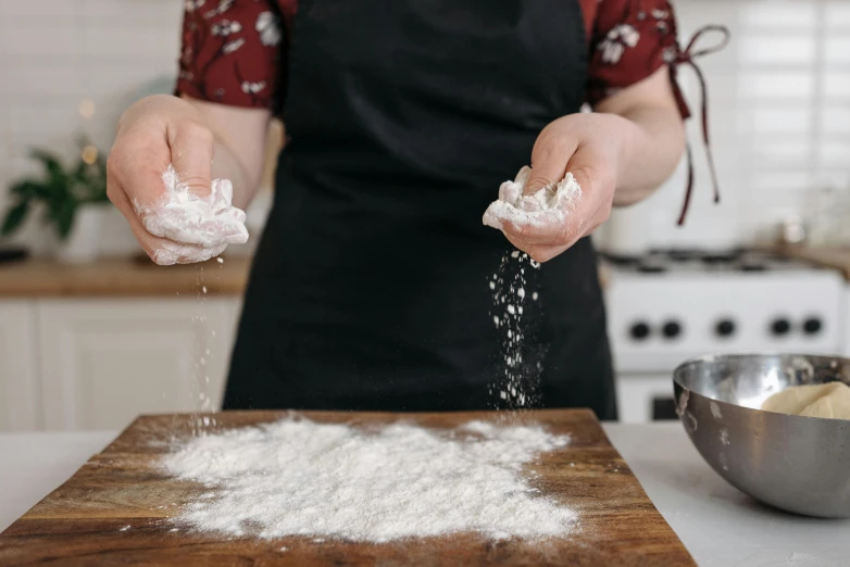 an adult in a kitchen with flour being poured into the air