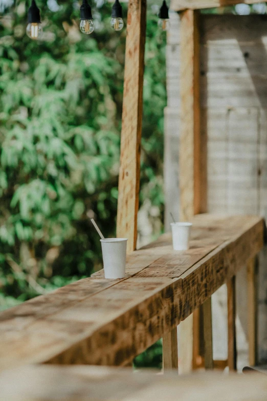 two coffee cups are on an outdoor bench