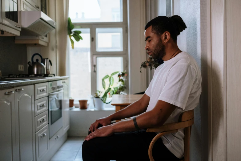 a man sits on a chair near a kitchen counter