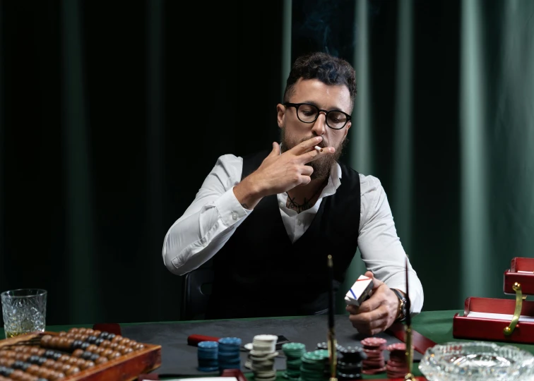 a man in glasses smoking a cigar while sitting at a desk