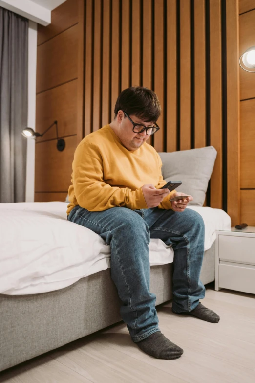 a man with glasses sitting on top of a bed