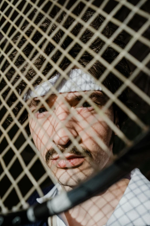 a man with his face obscured by a wire fence