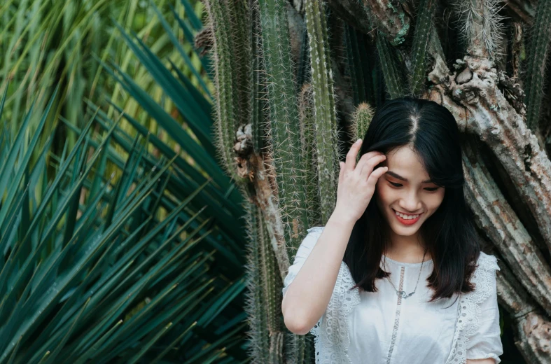 the woman in white dress is smiling by cactus trees