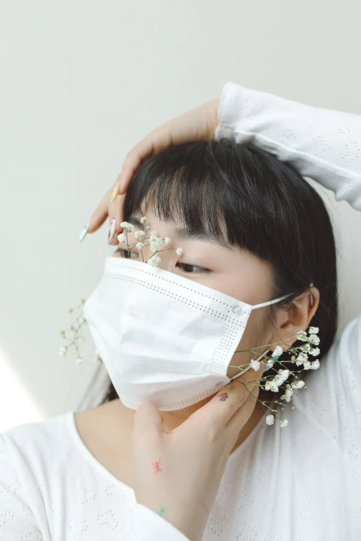 a young lady putting on her face mask with small flowers