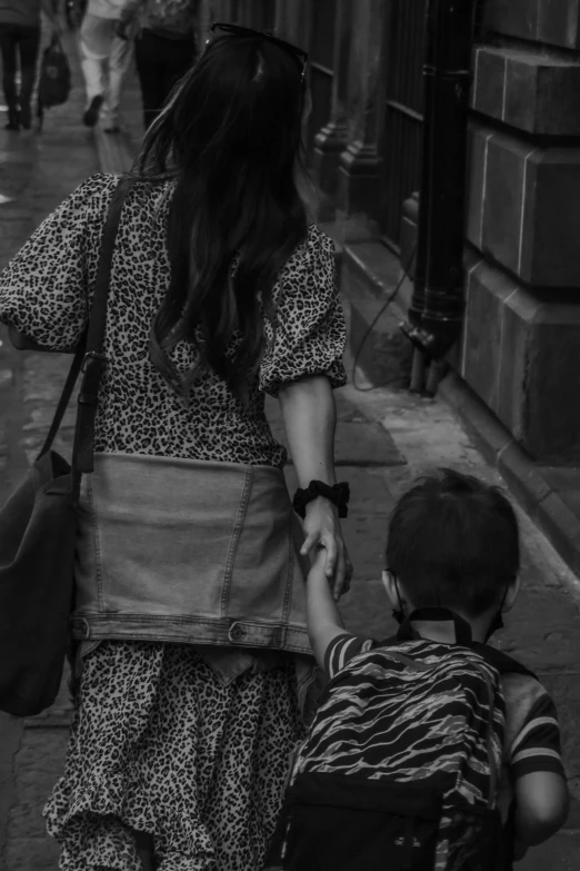 mother holding the hand of her child on a sidewalk