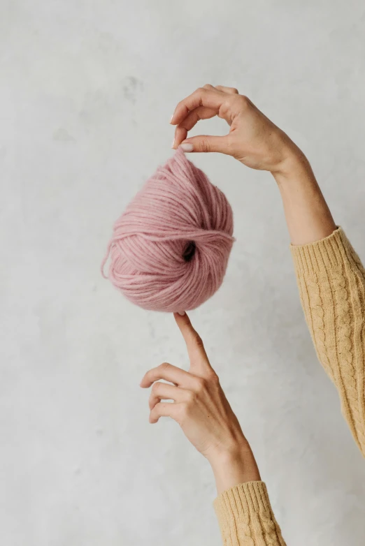 someone holding up a ball of yarn to hold it