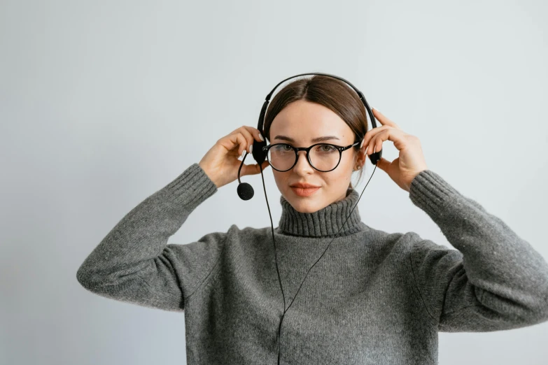 a woman wearing glasses and headphones while holding her hair up