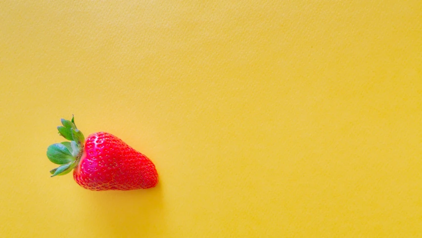 a red strawberry that is sitting on the ground