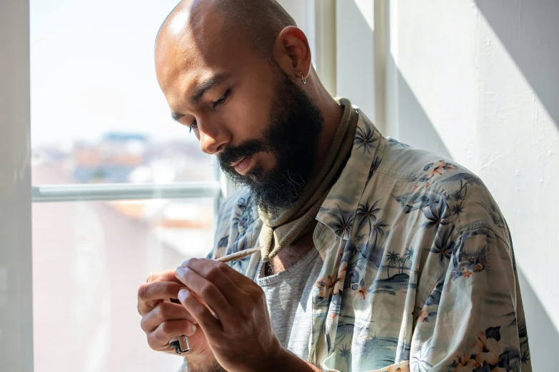 a man holding soing while sitting in front of a window