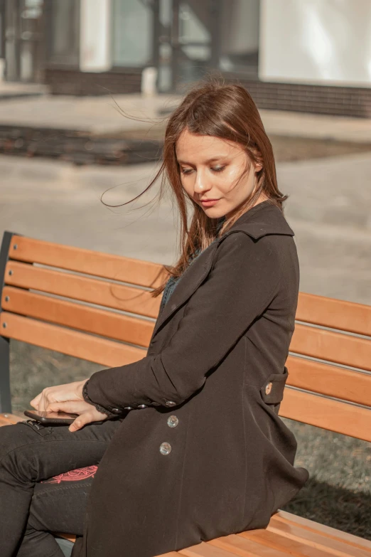 a woman is sitting on a bench looking down at her purse