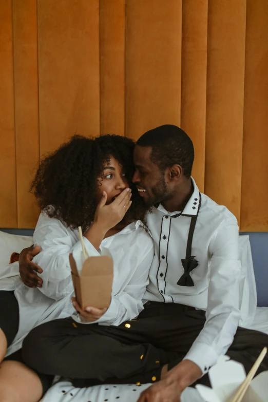 a couple sits together and laughs while they eat