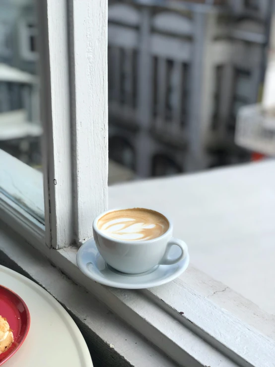 a cup of coffee on a saucer next to a plate with a doughnut on it