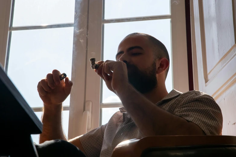 a man drinking out of his pipe while sitting down