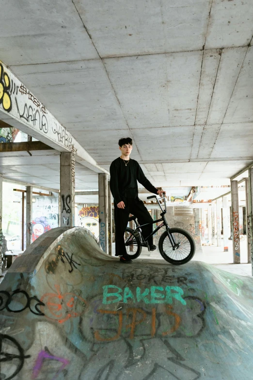 a guy is posing with a bike in a skate park