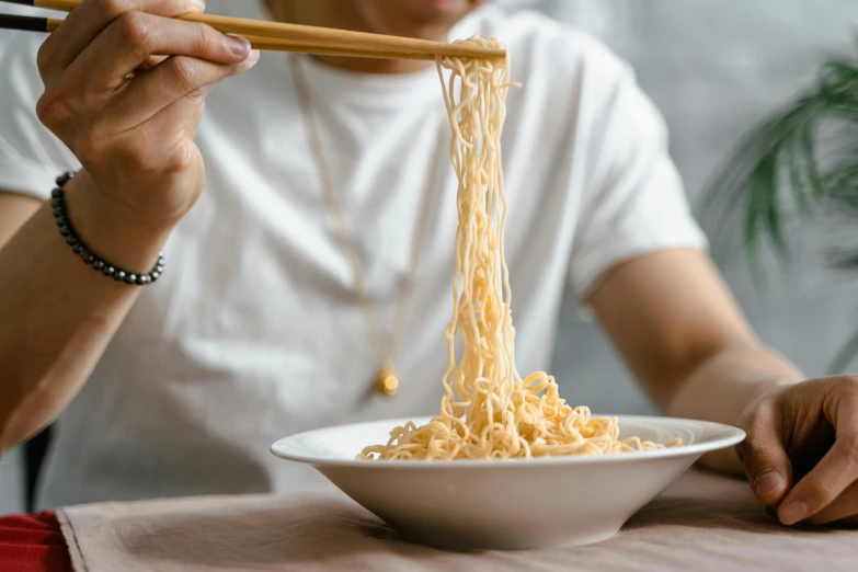 the woman is eating noodles at the table