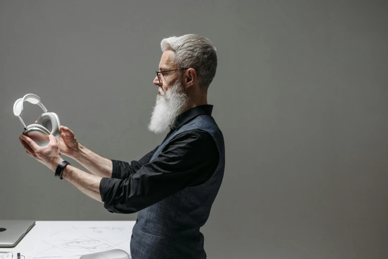 an elderly man standing in front of a computer holding glass objects