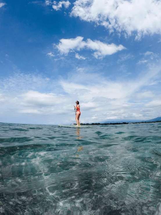 a woman standing on top of a surfboard in the ocean