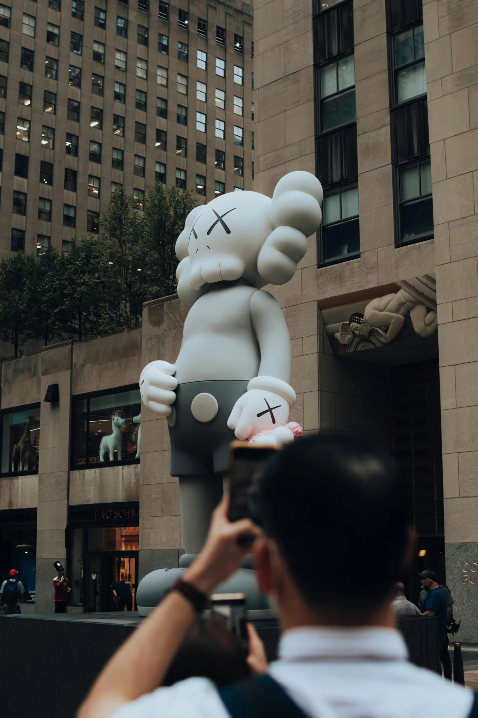 a man takes a po of a big balloon that has a bear on it