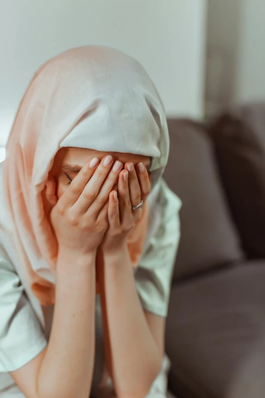 a woman in hijab covers her face and hands