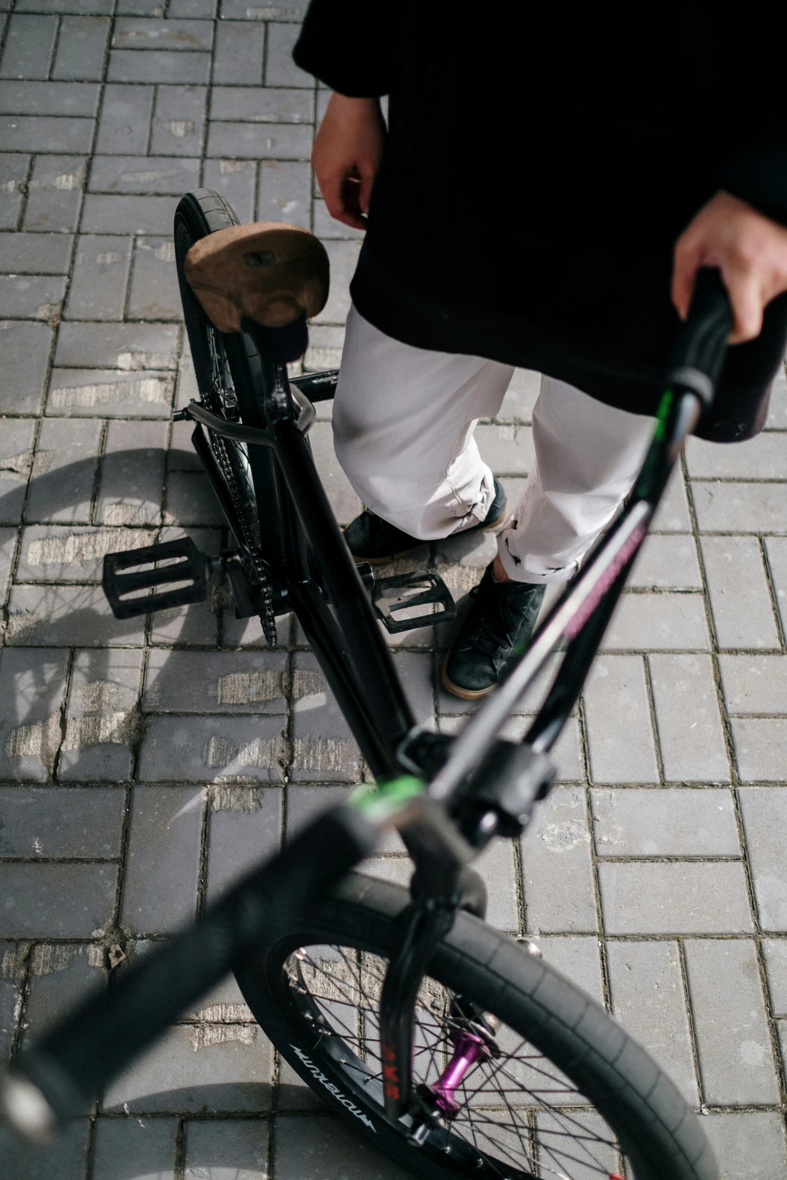 someone hing a bicycle with it's wheel on a brick street