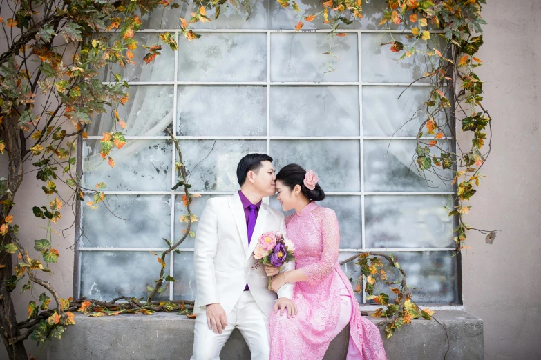 man and woman are kissing each other in front of a window with vines and flowers