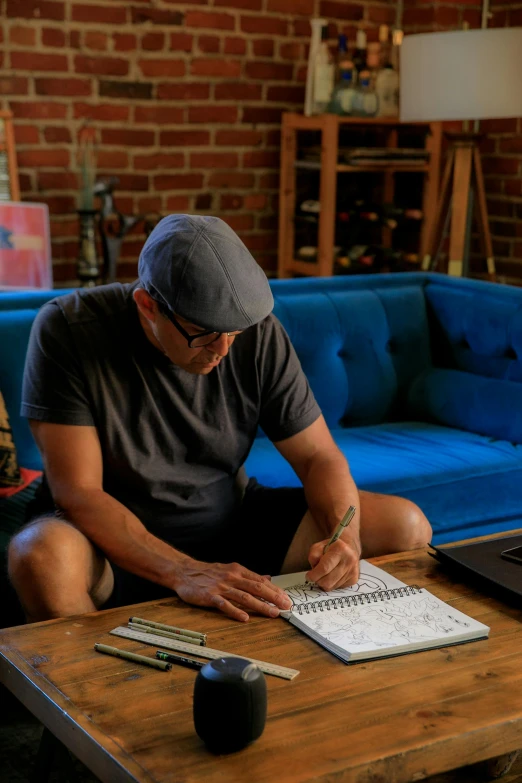 a man sitting on the floor writing on a notebook next to a keyboard