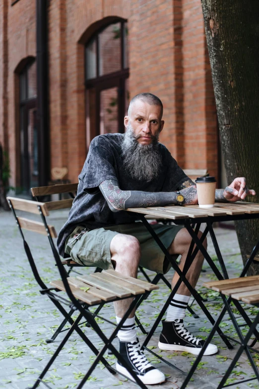 a man with a full beard sitting at a table outdoors