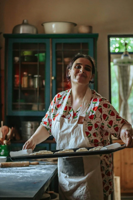 a lady preparing food at a stove with rolling pans